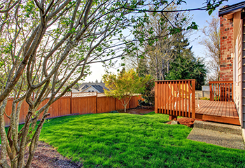 The image shows a newly constructed wooden walkout deck attached to the back of a house.